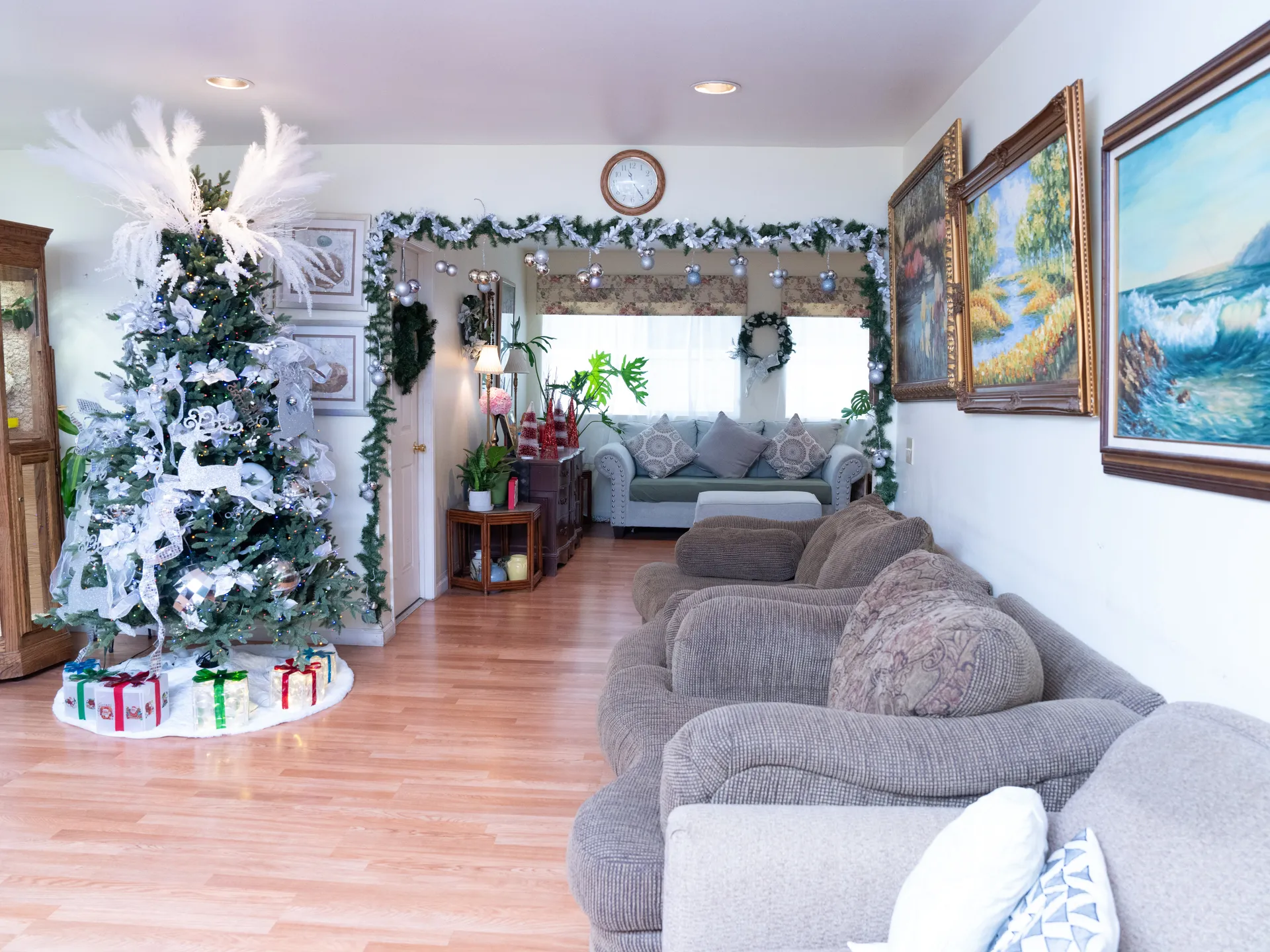 Spacious living room with comfortable gray sofas, decorated Christmas tree, and coastal artwork creating a warm home environment